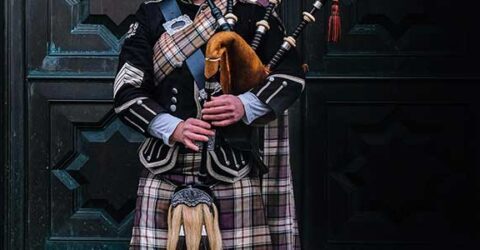 Man playing bagpipes in highland dress